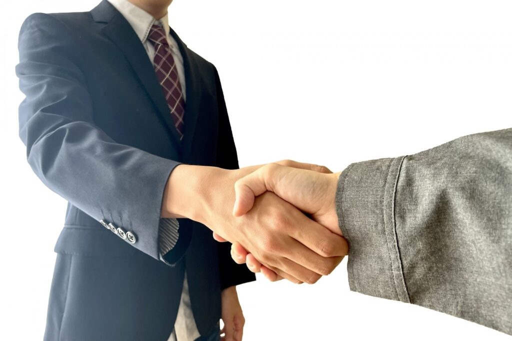 スーツ姿のビジネスマンが握手する場面
